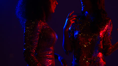 Close-Up-Of-Two-Women-In-Nightclub-Bar-Or-Disco-Dancing-Talking-And-Having-Fun-Together